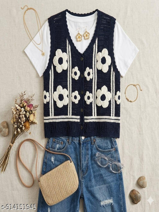Navy floral-patterned vest over a white shirt with blue jeans, accompanied by a straw bag and sunglasses on a textured surface.